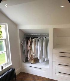 an empty closet with clothes hanging on the wall and drawers in front of it, next to a radiator