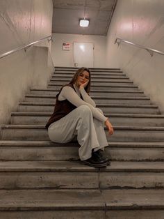 a woman is sitting on the stairs with her hand under her chin