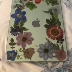 an ipad case with flowers on it sitting on top of a white bed spreader