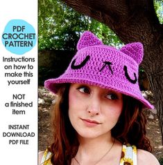 a woman wearing a pink crochet hat with a cat face on it's brim