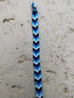 a blue and white crocheted lanyard on the sand