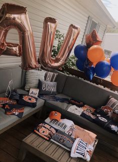 a couch sitting on top of a wooden floor next to balloons and t - shirts