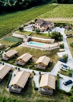 an aerial view of several houses in the middle of a field with cars parked nearby