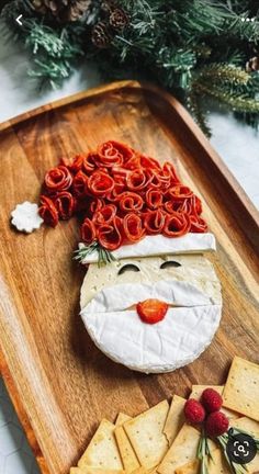 a wooden tray topped with crackers and cheese covered in santa claus's face