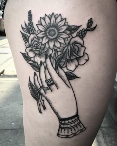 a woman's thigh with flowers in her hand on the side of her leg