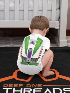 a small child sitting on the floor in front of a black and orange carpeted area