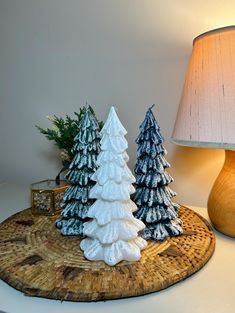 two small christmas trees on a tray next to a lamp