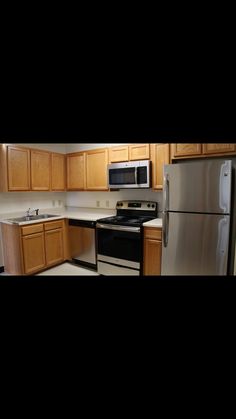 an empty kitchen with stainless steel appliances and wood cabinets