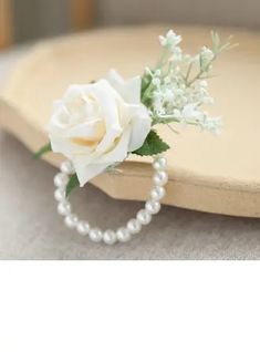 a white rose and pearl necklace on a tray