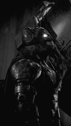 black and white photograph of iron man in the rain with his helmet on top of him