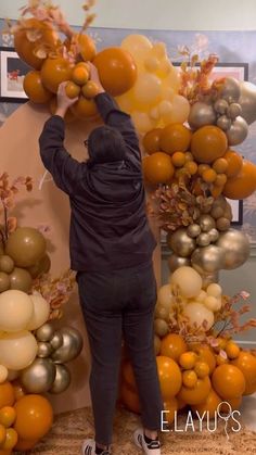 a person standing in front of a bunch of oranges and balloons on a wall