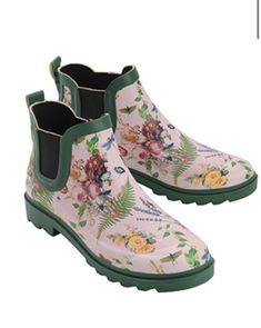 a pair of white boots with flowers and leaves on the bottom, one has green rubber outs