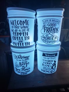 four plastic buckets sitting on top of a table with words painted on them in different languages