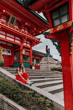 a woman sitting on steps in front of a red building