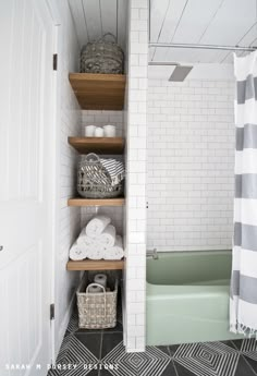 a bathroom with black and white tile flooring and shelving in the shower area