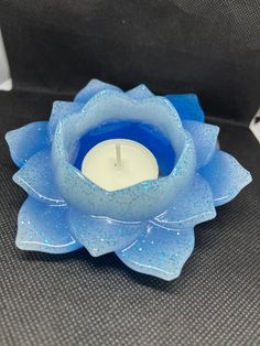 a candle that is sitting inside of a blue flower shaped container with water droplets on it