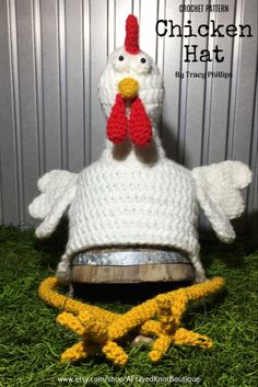 a crocheted chicken hat sitting on top of a wooden barrel in the grass