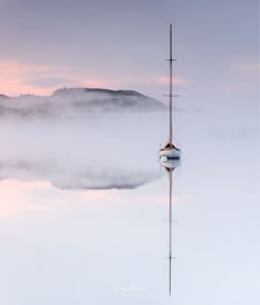 a sailboat floating in the water on a foggy day