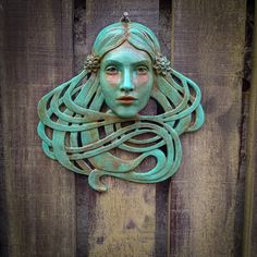 a woman's face is carved into the side of a wooden fence with braids on it