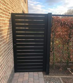 an open black gate in front of a brick wall