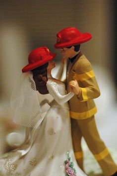 a wedding cake topper with a bride and groom in fireman's hats