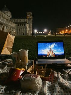 an open laptop computer sitting on top of a bed next to a basket of food