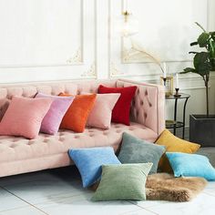 a pink couch with six different colored pillows sitting on it's back and side