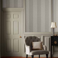 a chair sitting in front of a lamp on top of a wooden floor next to a door