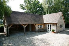 a large wooden building sitting in the middle of a gravel covered area next to trees