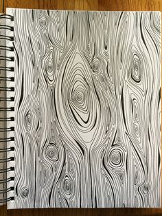 a spiral notebook with black and white lines on the cover, sitting on a wooden surface