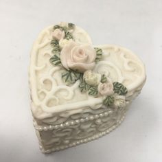 a white heart shaped box with flowers on it