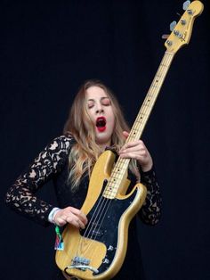 a woman is playing an electric guitar on stage with her mouth open and tongue out