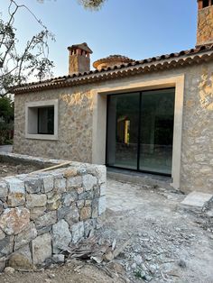 a stone building with an open door and windows on the outside, next to a rock wall