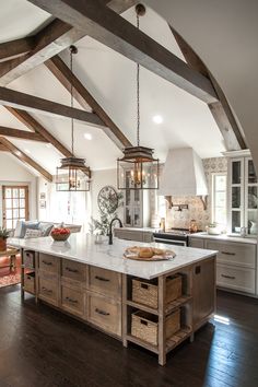 a large kitchen with an island in the center and lots of wood beams on the ceiling