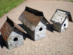 three metal bird houses sitting on the ground