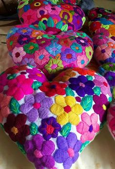 several colorful pillows are arranged on a white surface and one is shaped like a heart