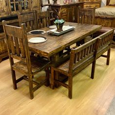 a wooden table with chairs and plates on it in a room filled with furniture items