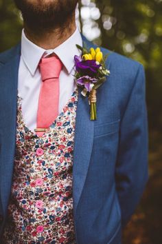 a man in a suit and tie with flowers on his lapel