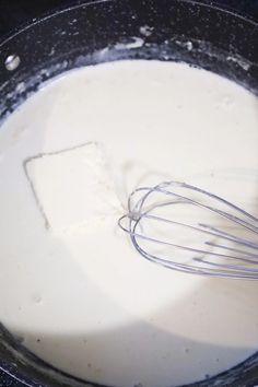 a whisk in a pan filled with milk