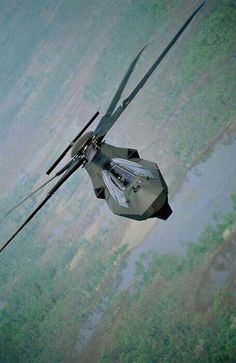 an aerial view of a helicopter flying in the sky over trees and land below it