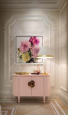 a pink table with a lamp and painting on the wall