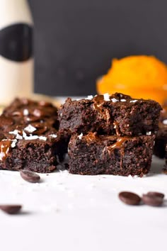 chocolate brownies with coconut flakes on a white surface next to an orange and bottle of wine