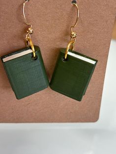 two green books are hanging from gold earwires