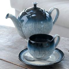 a tea pot and saucer sitting on a wooden table