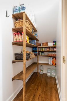 an organized pantry with wooden shelves and baskets on the bottom shelf, along with other food items