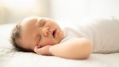 a baby sleeping on top of a white blanket