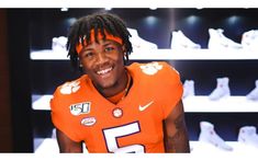 a man with dreadlocks and an orange football uniform is smiling for the camera