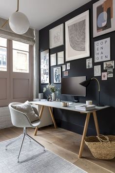 a home office with black walls and pictures on the wall