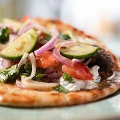 a flatbread pizza topped with cucumbers, onions and other veggies