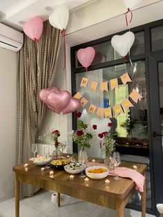 a wooden table topped with lots of food and balloons